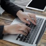 Man's hands typing on a laptop